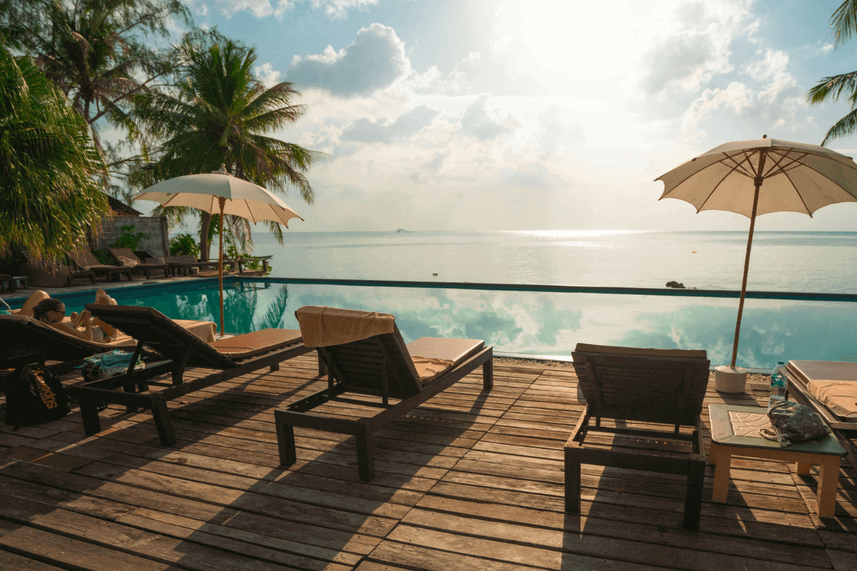 Sun loungers and umbrellas by an infinity pool overlooking the ocean at sunset Sun loungers and umbrellas by an infinity pool overlooking the ocean at sunset